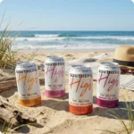 Four colorful seltzer cans on beach
