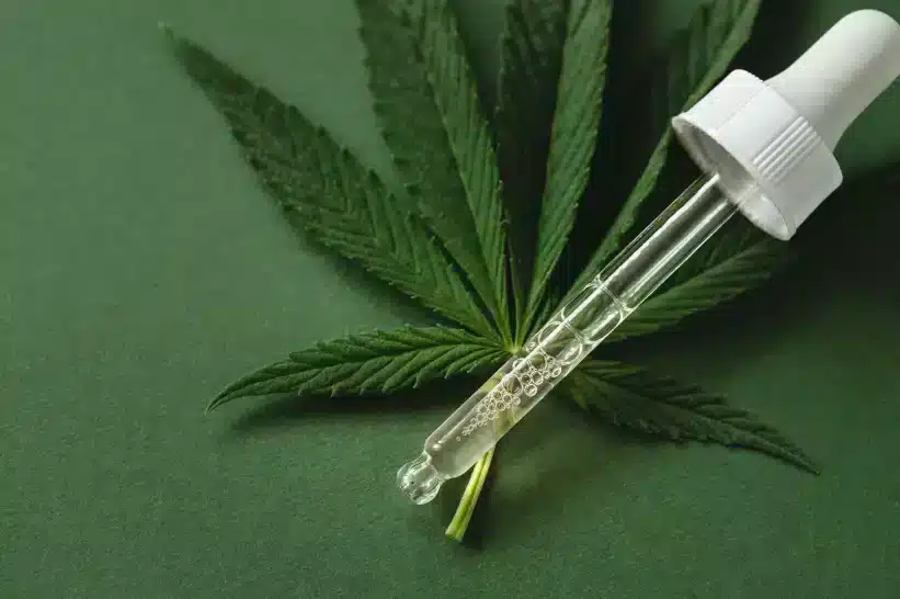 Delta 8 tincture and a cannabis leaf side by side