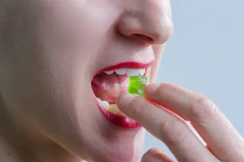 a close up of a woman eating an energizing gummy