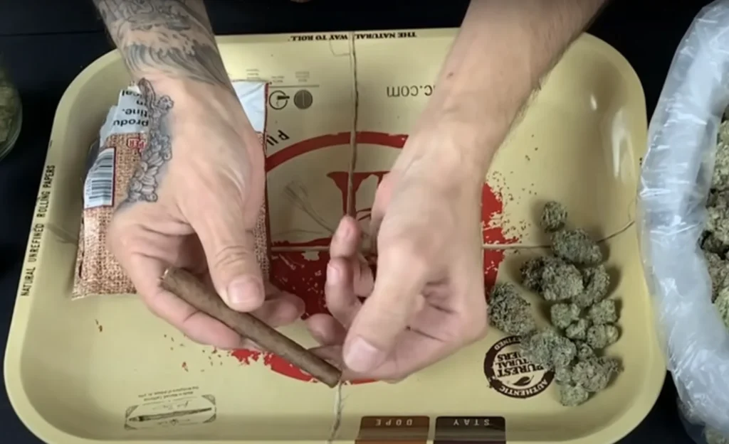 a person pulling a backwood tab to unravel the blunt.