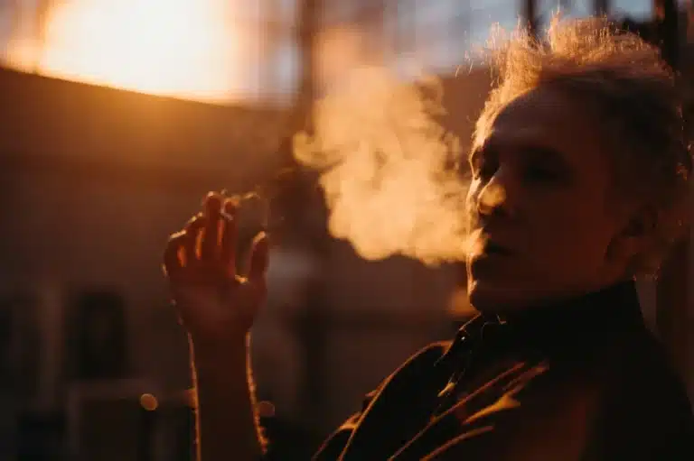 a man smoking a joint, emitting a THC M byproduct