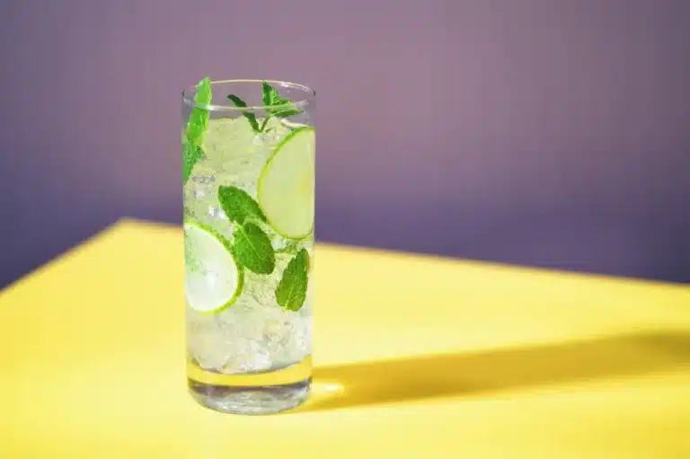 a glass of THC mocktail with lime slices and mint leaves