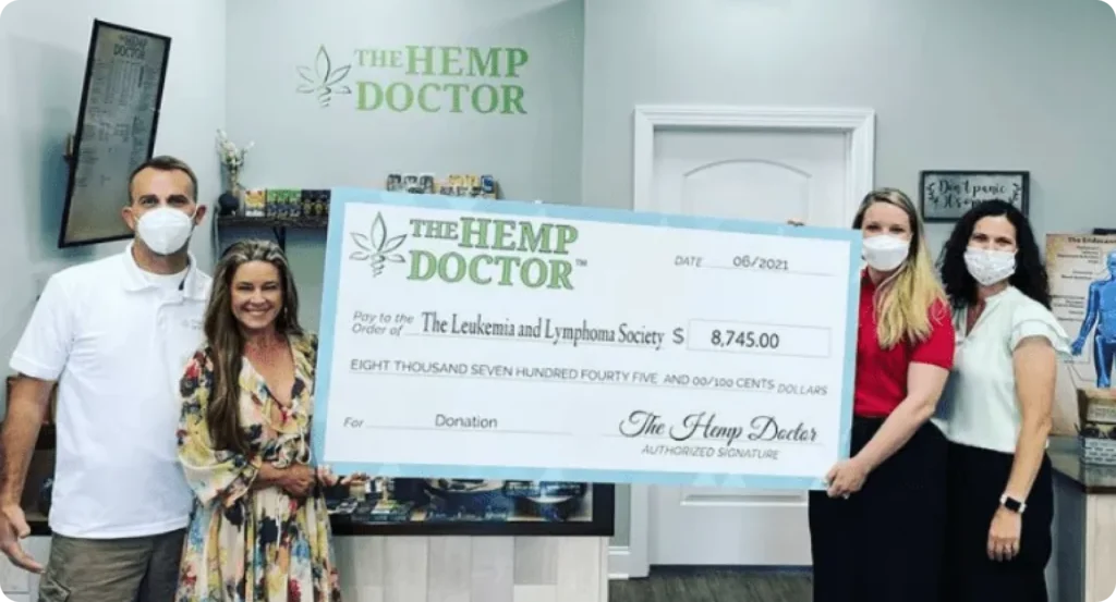 The Hemp Doctor team holding an oversized $8,745 donation check made out to The Leukemia and Lymphoma Society